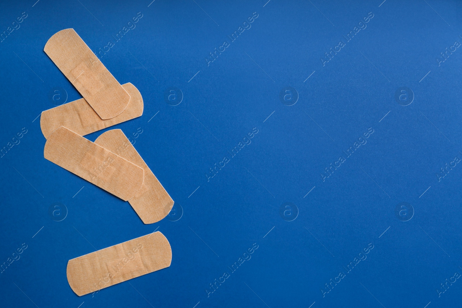 Photo of Sticking plasters on blue background, flat lay. Space for text