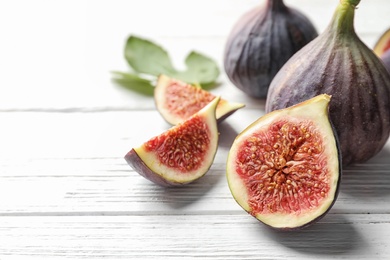 Whole and cut purple figs on wooden background. Space for text