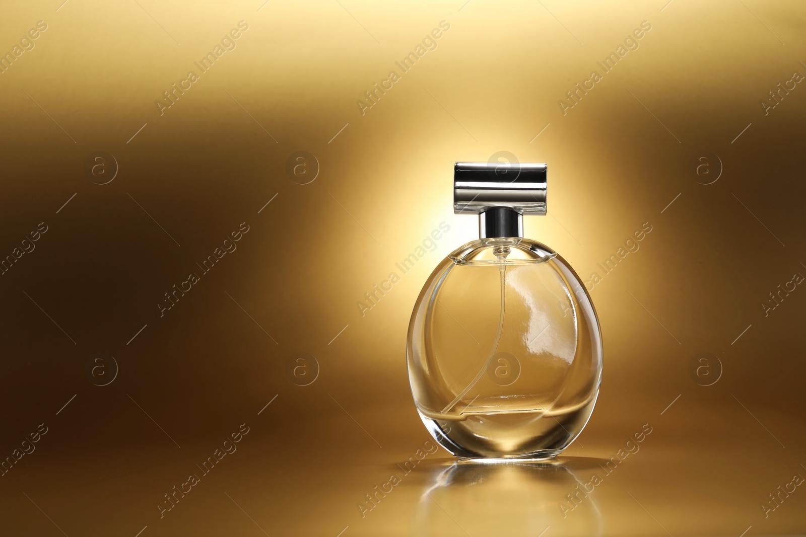 Photo of Luxury women's perfume. Sunlit glass bottle on golden background, space for text