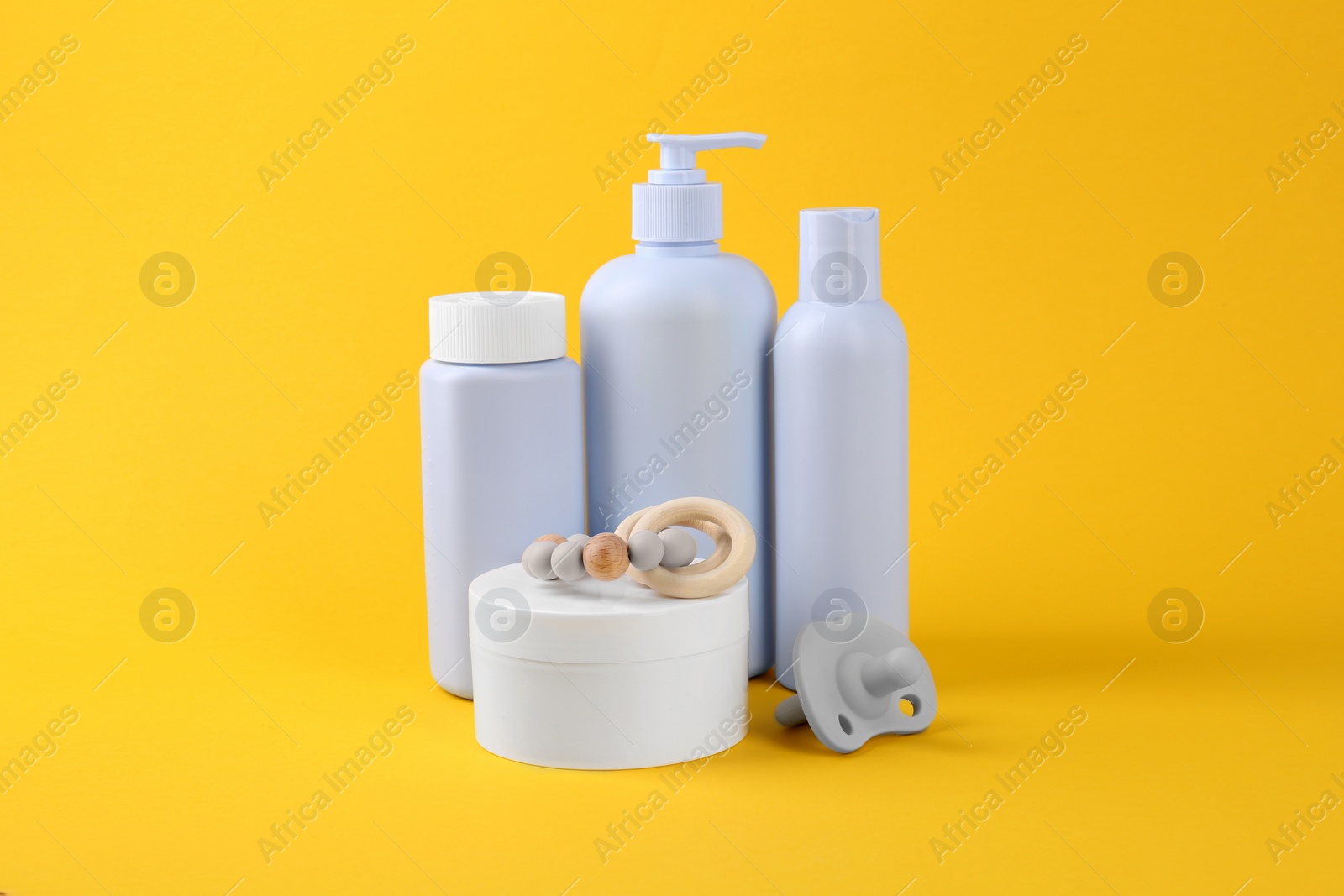 Photo of Different skin care products for baby and pacifier on yellow background