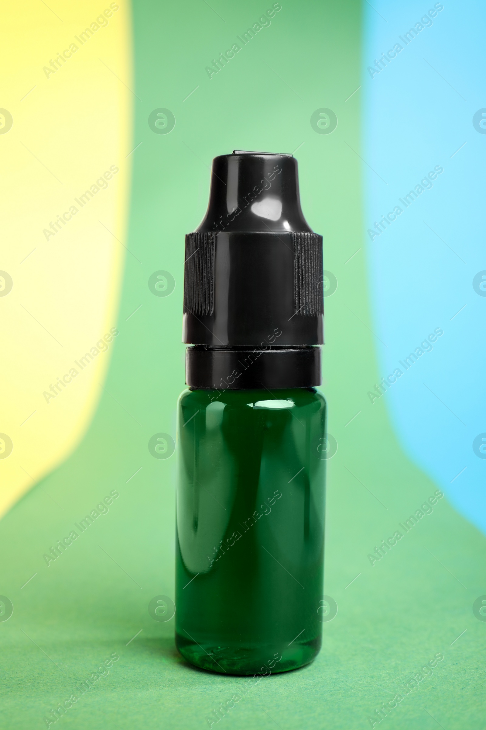 Photo of Bottle with green food coloring on bright background