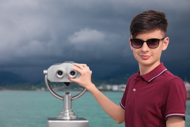 Teenage boy near mounted binoculars at sea