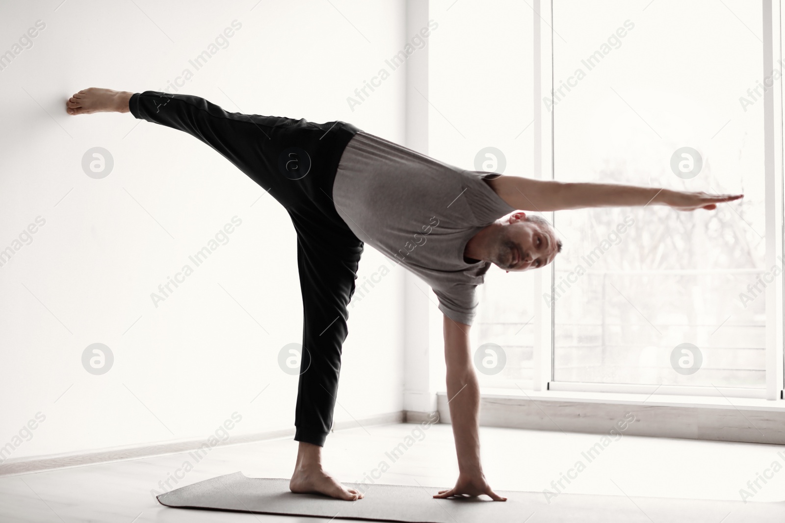 Photo of Sporty man practicing yoga indoors