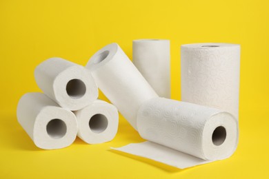 Photo of Many rolls of paper towels on yellow background
