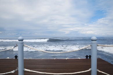 Photo of Picturesque view of sea with waves behind pier fence