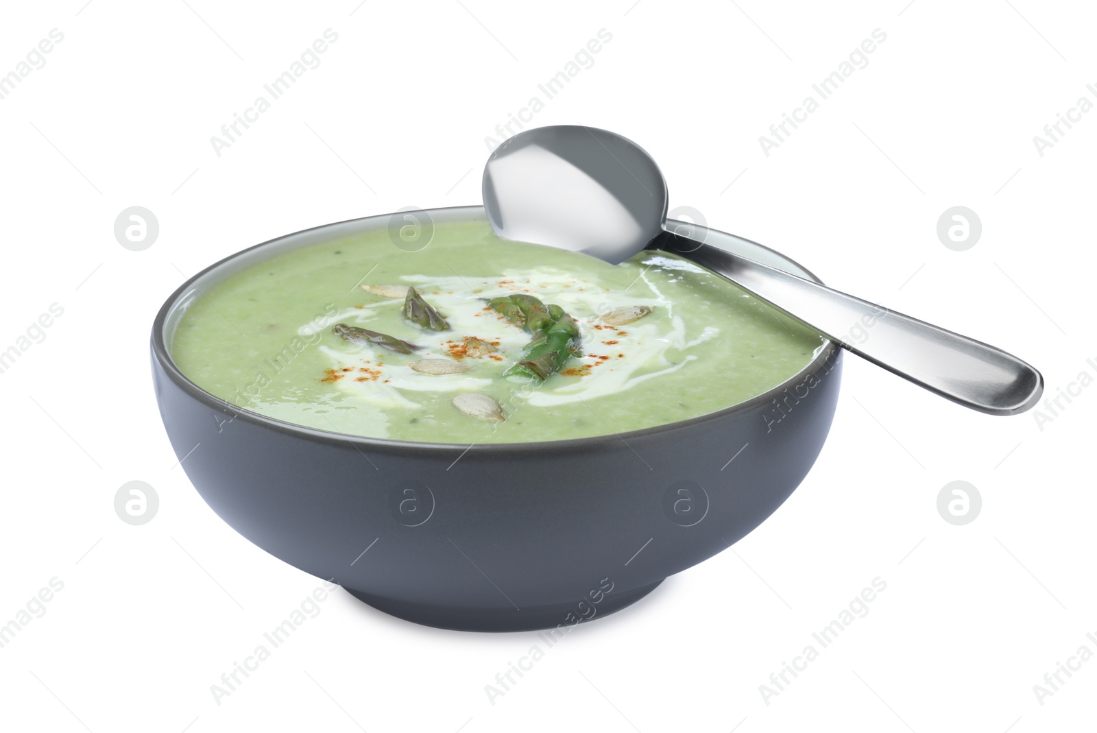 Photo of Delicious asparagus soup with pumpkin seeds and spoon on white background