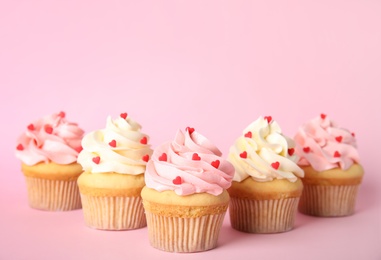 Photo of Tasty cupcakes with heart shaped sprinkles on pink background. Valentine's Day celebration