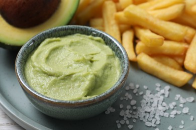 Delicious french fries, guacamole dip and avocado on plate, closeup