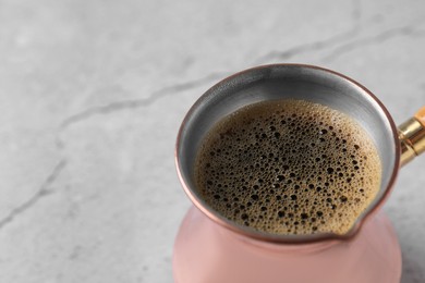 Photo of Turkish coffee in cezve on light grey table, closeup. Space for text