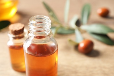 Glass bottles with jojoba oil on wooden table, closeup. Space for text