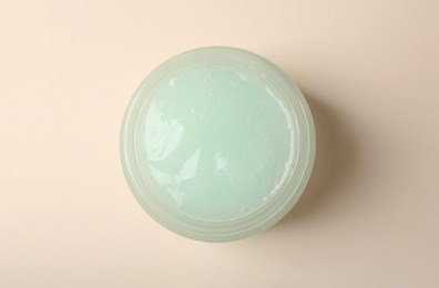 Photo of Jar of aloe gel on beige background, top view