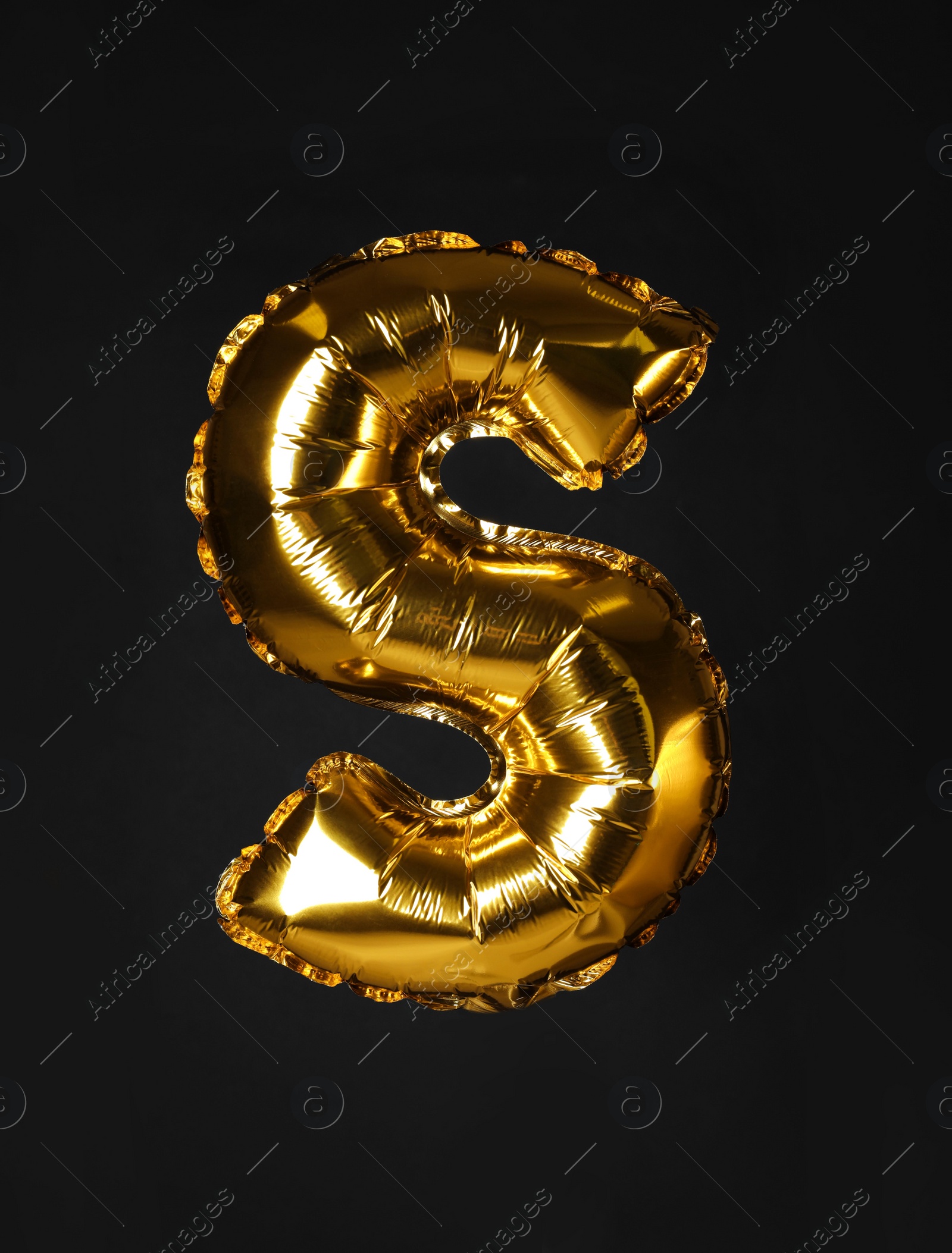 Photo of Golden letter S balloon on black background