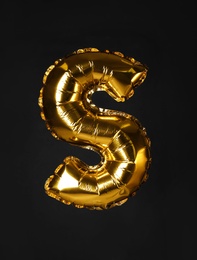 Photo of Golden letter S balloon on black background