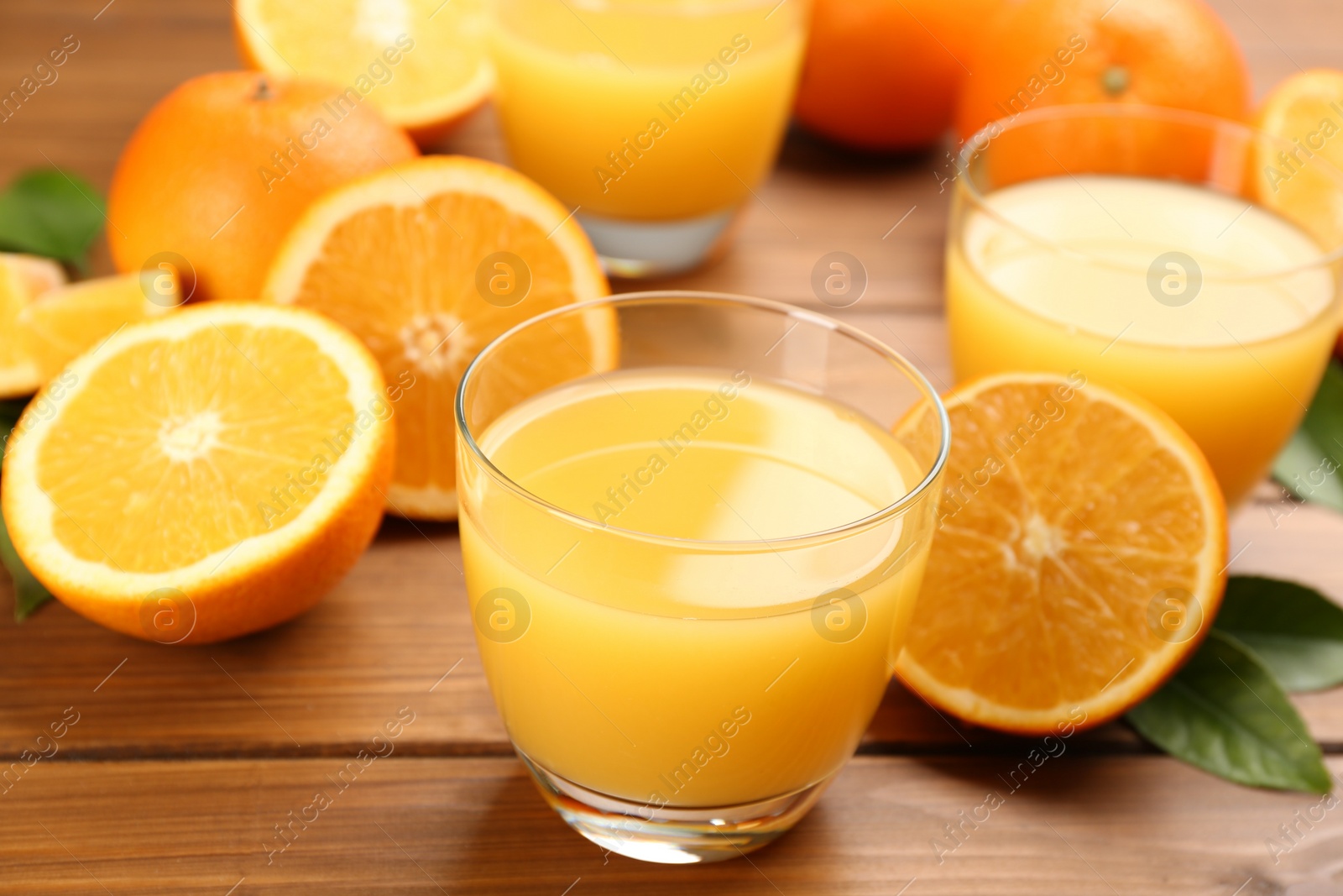 Photo of Delicious orange juice and fresh fruits on wooden table, closeup