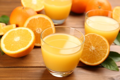 Delicious orange juice and fresh fruits on wooden table, closeup