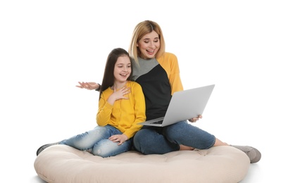 Mother and her daughter using video chat on laptop against white background