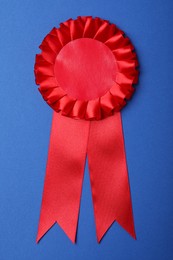 Photo of Red award ribbon on blue background, top view