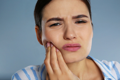 Image of Young woman suffering from toothache on grey background