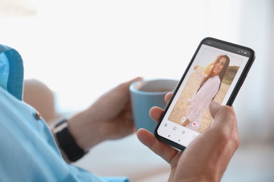 Image of Man visiting dating site via smartphone indoors, closeup