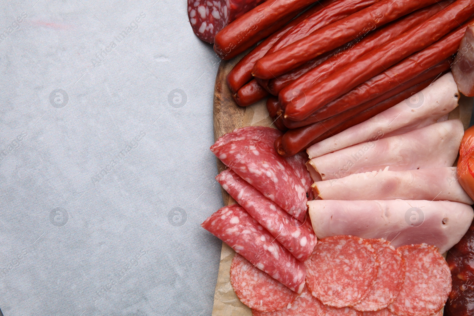 Photo of Different types of sausages on light grey table, flat lay. Space for text