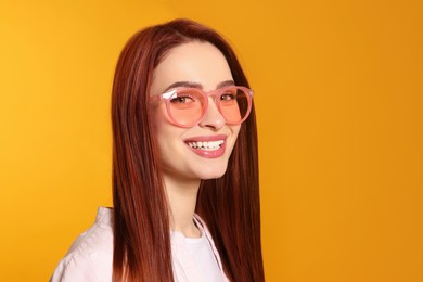 Photo of Happy woman with red dyed hair and sunglasses on orange background