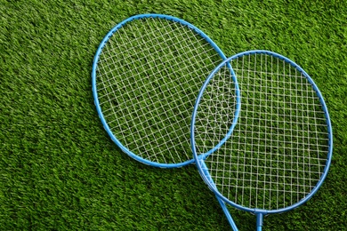 Photo of Badminton rackets on green grass outdoors, above view. Space for text