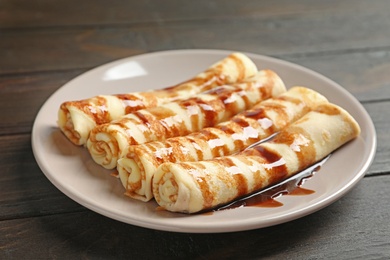 Photo of Thin pancakes served with chocolate syrup on plate