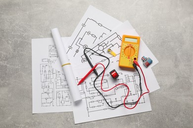 Wiring diagrams, digital multimeter and connectors on grey table, flat lay