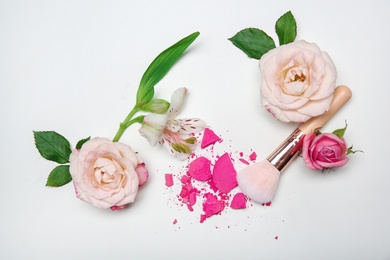 Flat lay composition with makeup brush and flowers on white background