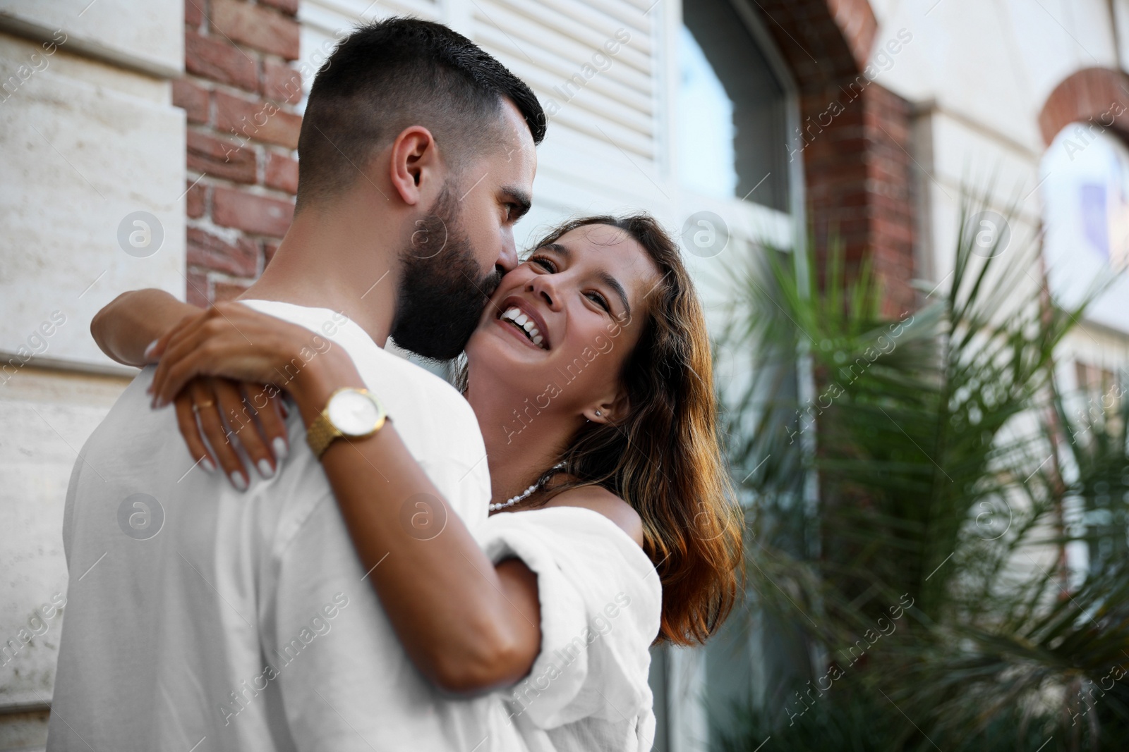 Photo of Handsome young man kissing his beautiful girlfriend on city street