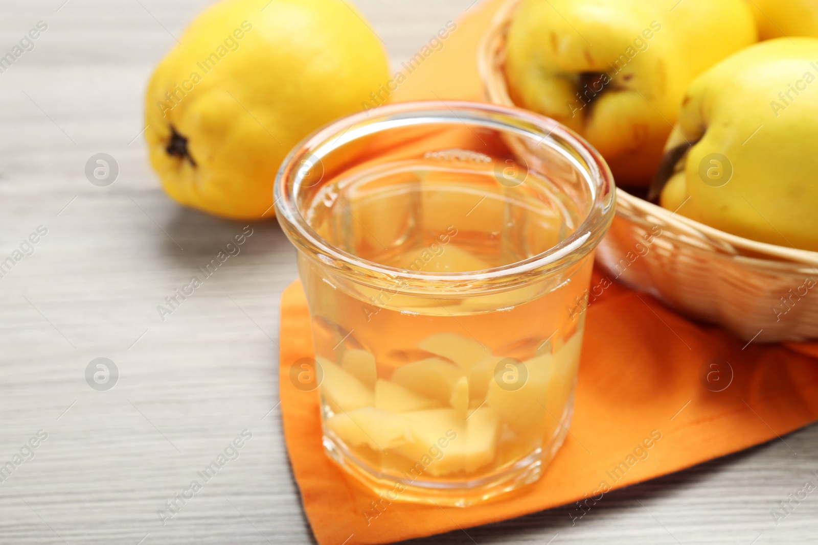 Photo of Delicious quince drink in glass and fresh fruits on wooden table, closeup