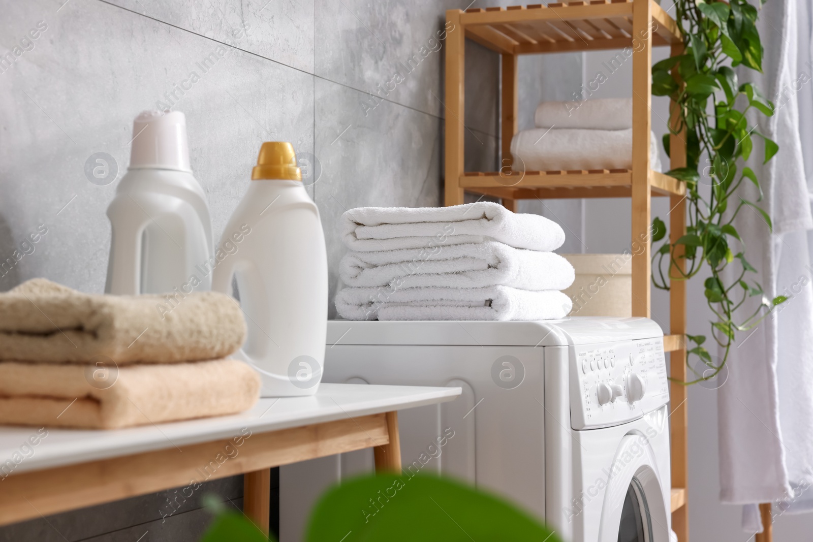 Photo of Soft towels, detergents, bench and washing machine indoors