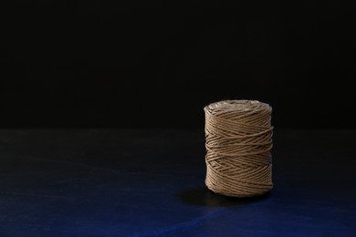 Photo of Spool of twine on table against black background, space for text