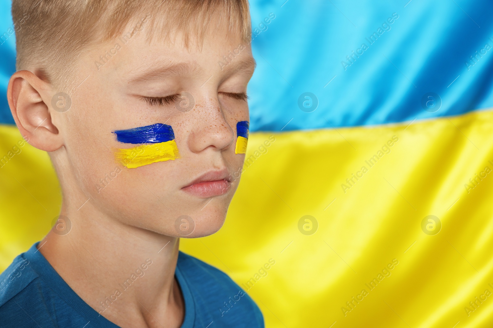 Photo of Little boy near Ukrainian flag, closeup. No war concept