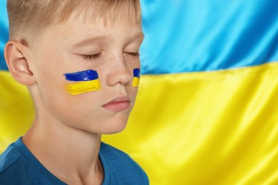 Little boy near Ukrainian flag, closeup. No war concept