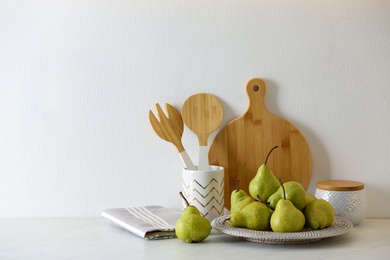 Photo of Plate with fresh ripe pears on white table. Space for text