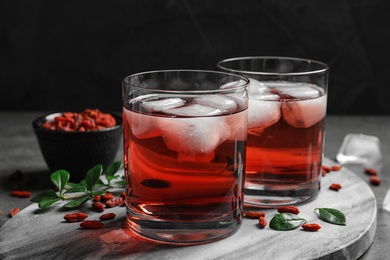 Photo of Healthy goji juice with ice in glasses on table