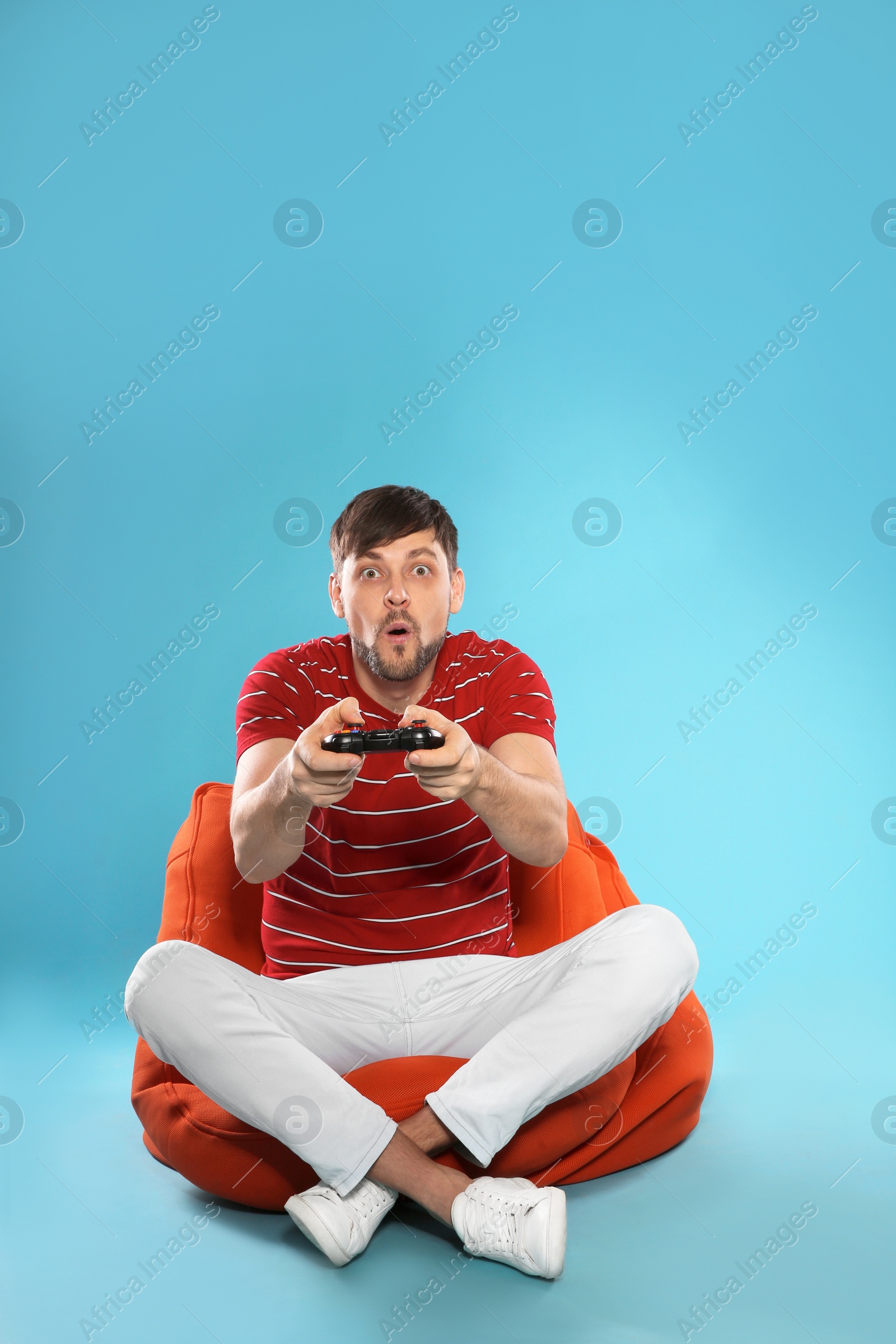 Photo of Emotional man playing video games with controller on color background. Space for text