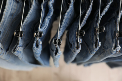 Photo of Top view of hangers with stylish jeans on light background, closeup