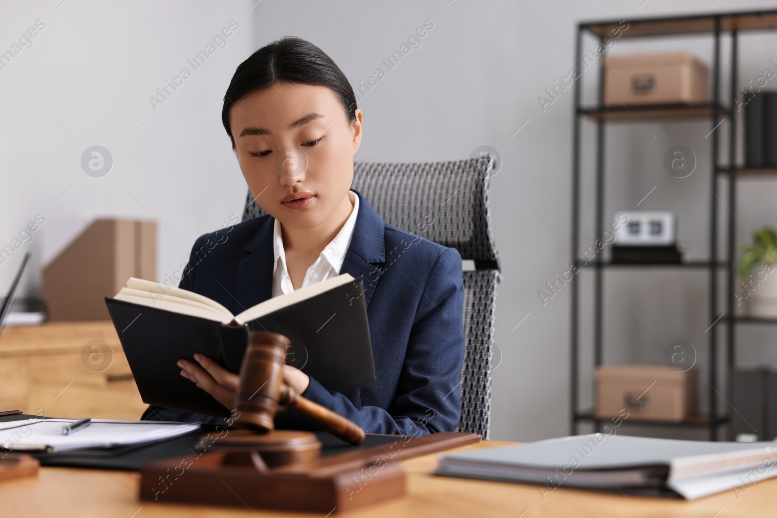 Photo of Notary reading book at table in office