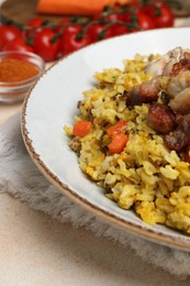 Photo of Delicious pilaf with meat, carrot and garlic on beige textured table, closeup
