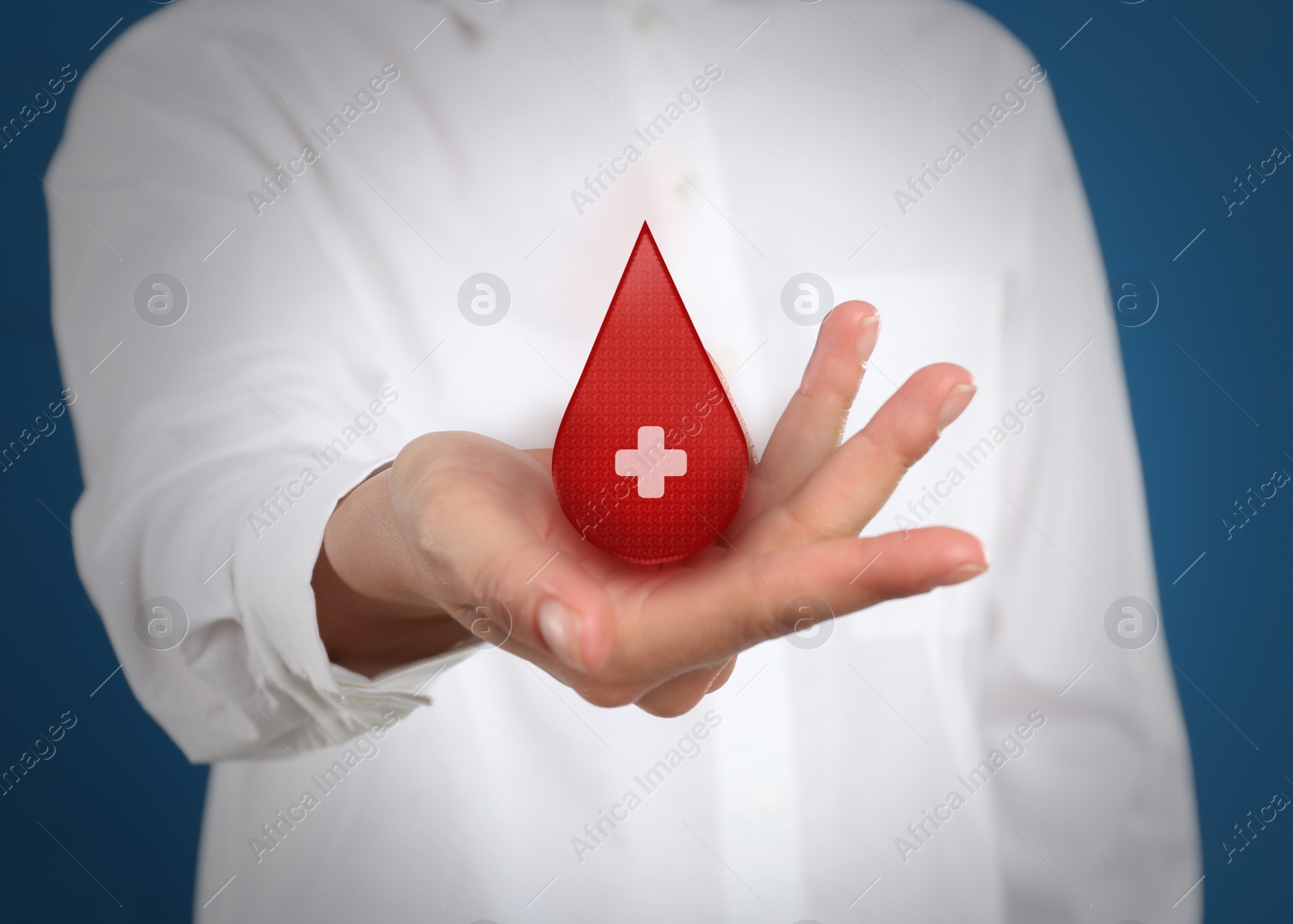 Image of Woman holding red drop in hand on blue background, closeup. Blood donation concept