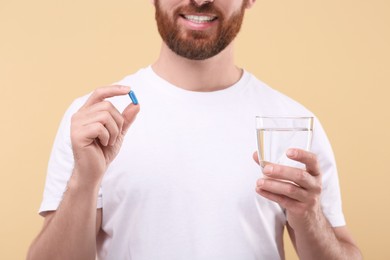 Photo of Man with glass of water and pill on beige background, closeup
