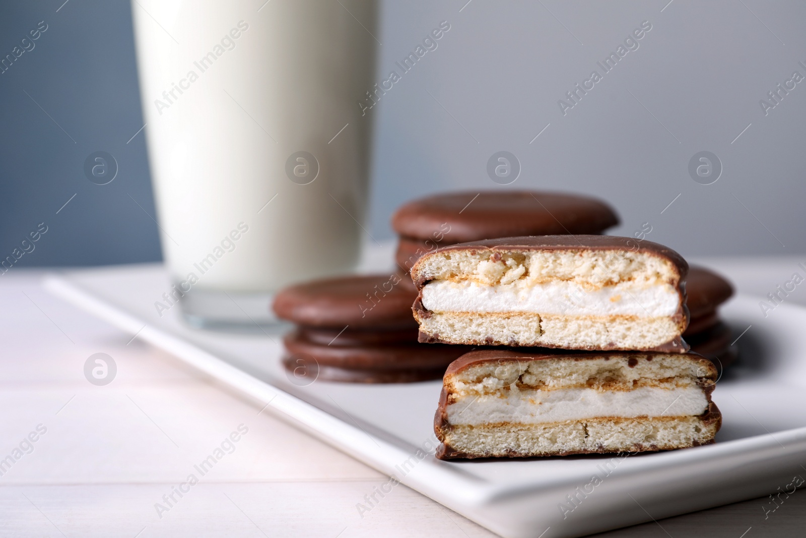 Photo of Tasty choco pies and milk on white wooden table, closeup view. Space for text