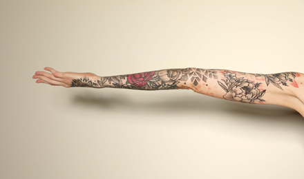 Photo of Woman with colorful tattoos on arm against white background, closeup