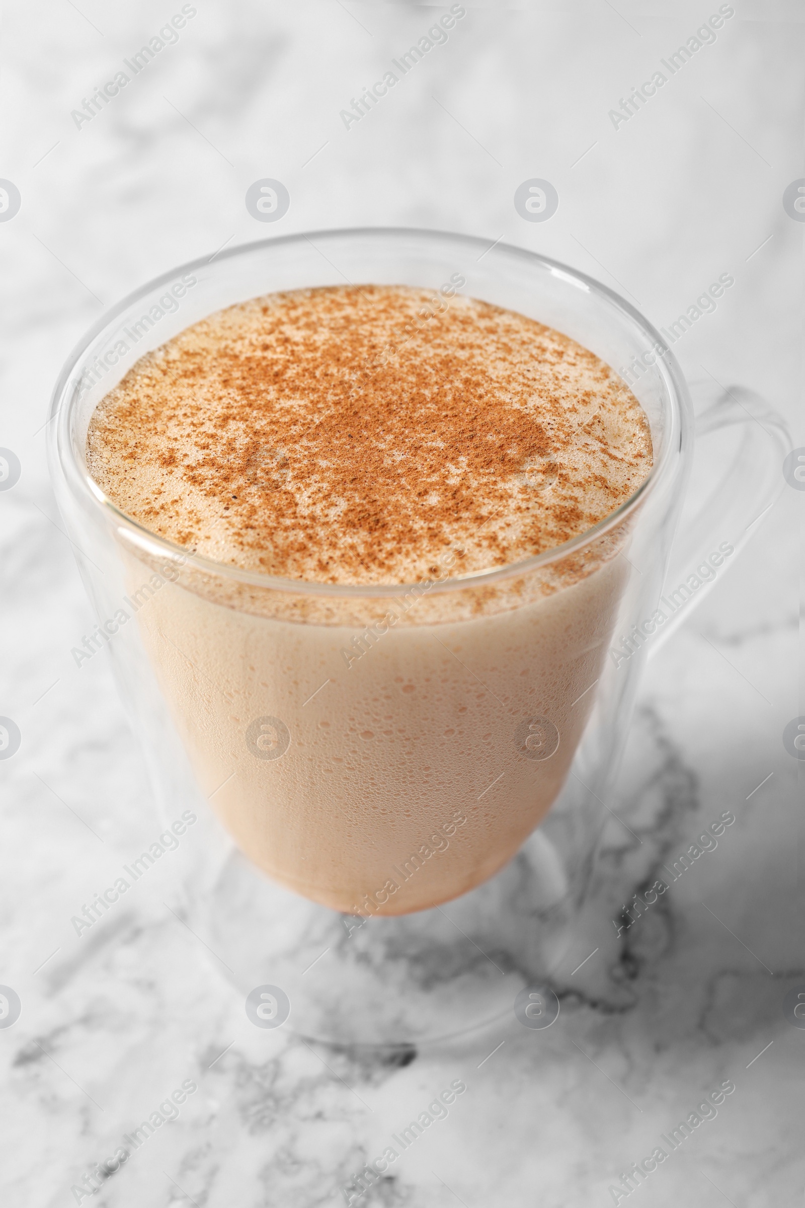 Photo of Glass cup of delicious eggnog on white marble table