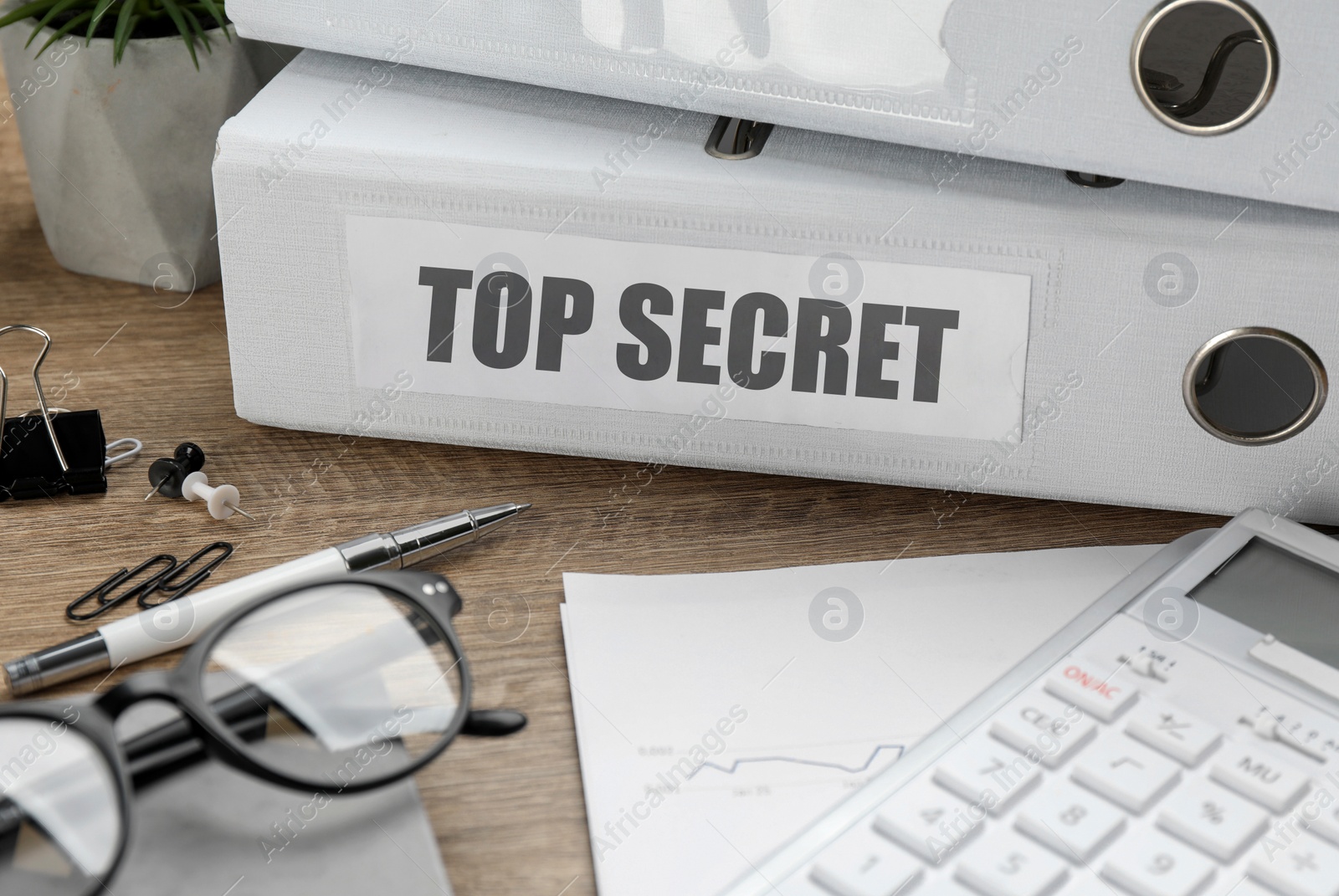 Image of Top Secret stamp. Stationery, glasses and calculator on wooden table, closeup