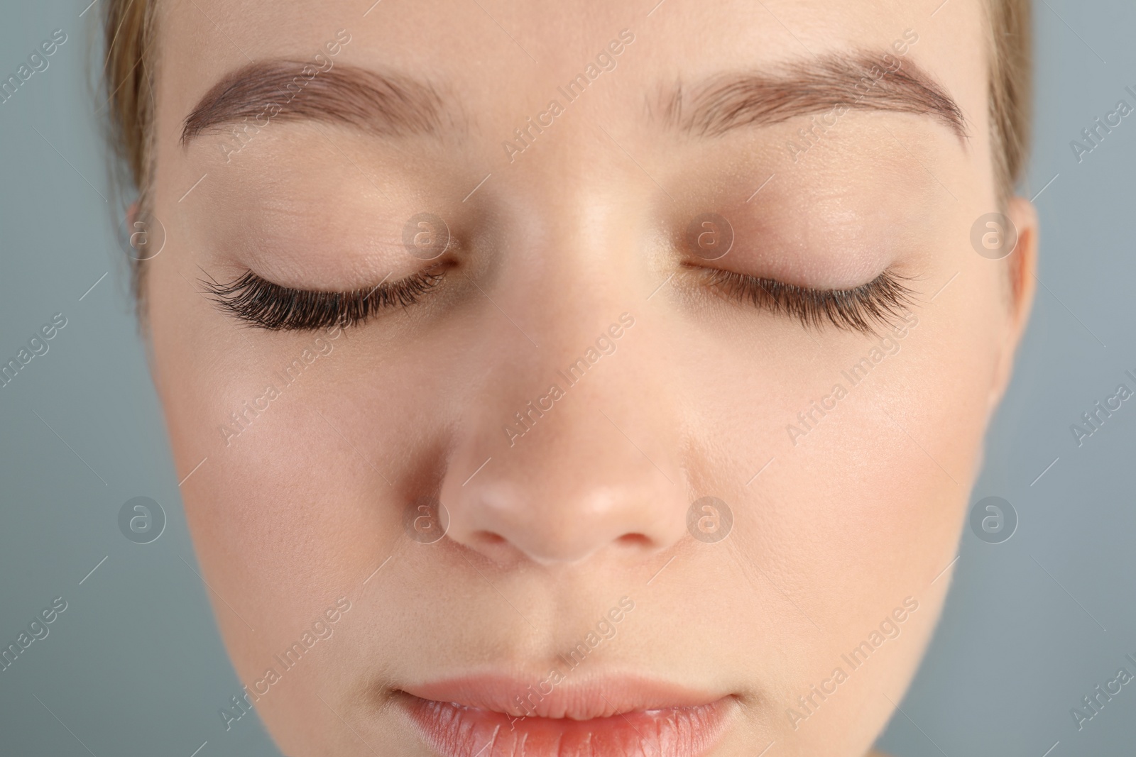 Photo of Young woman with beautiful eyelashes on gray background, closeup. Before and after extension procedure