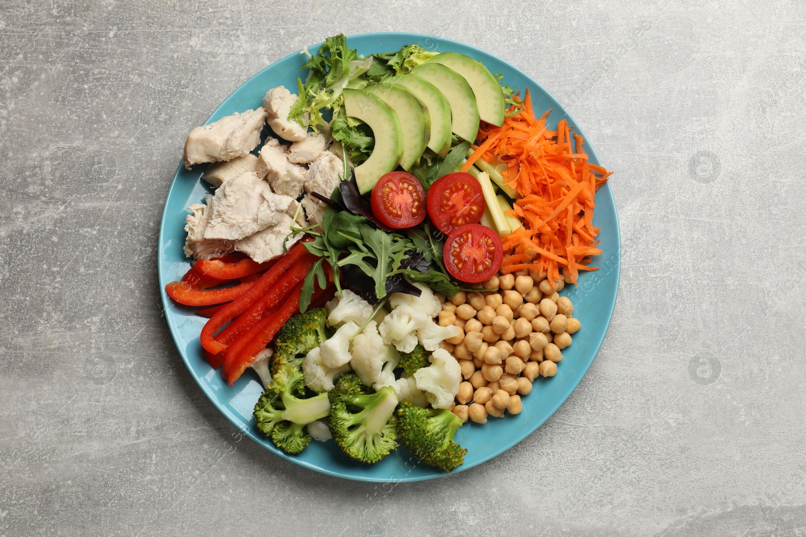 Photo of Balanced diet and healthy foods. Plate with different delicious products on grey table, top view