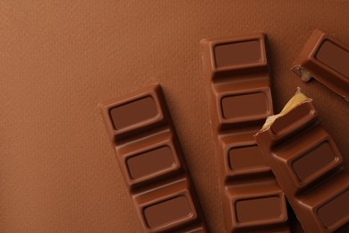 Delicious chocolate bars on brown background, flat lay